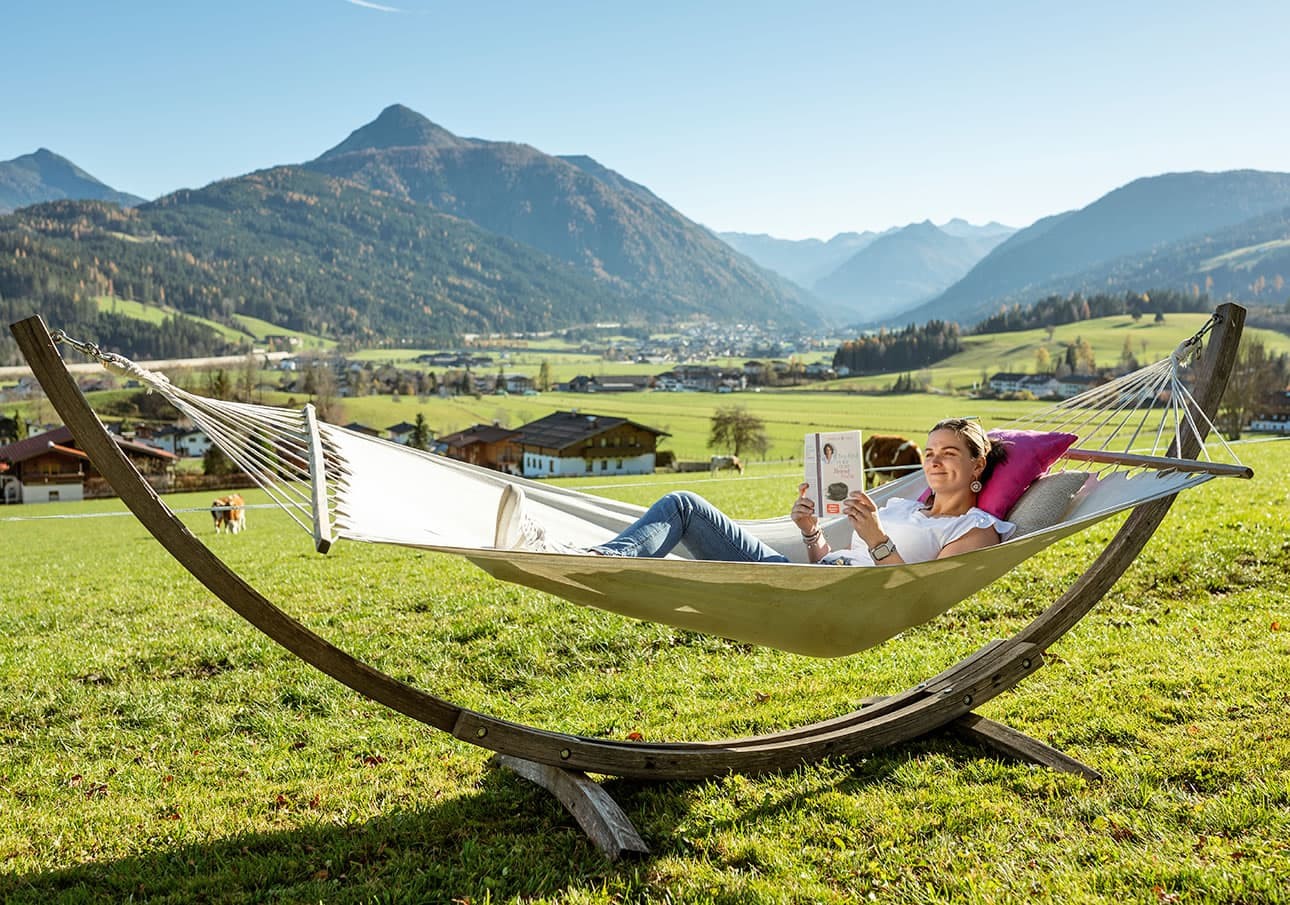 Person entspannt in Hängematte und liest ein Buch, mit Panoramablick über Flachau