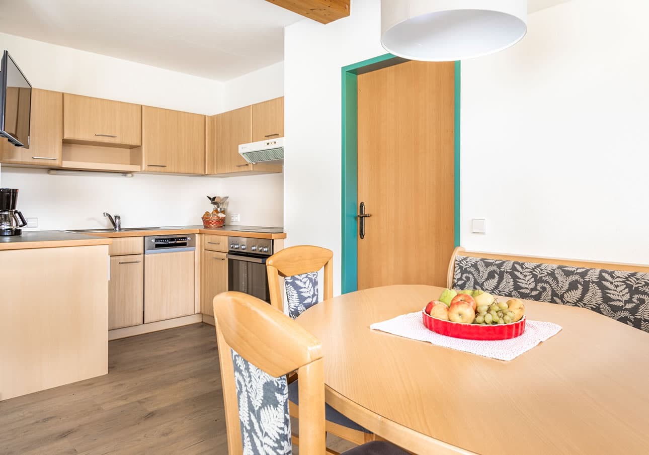 A cozy kitchen with wooden cabinets and a dining table topped with a fruit bowl