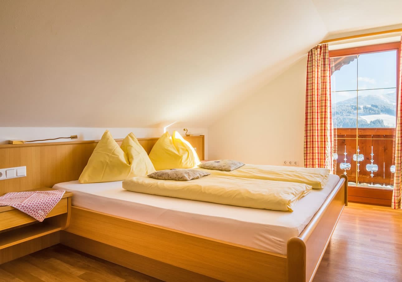 Cozy bedroom with yellow bedding, wooden furniture, and a mountain view through the window