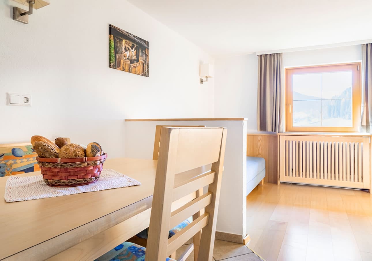 A cozy dining area with a bread basket on the table near a sunlit window