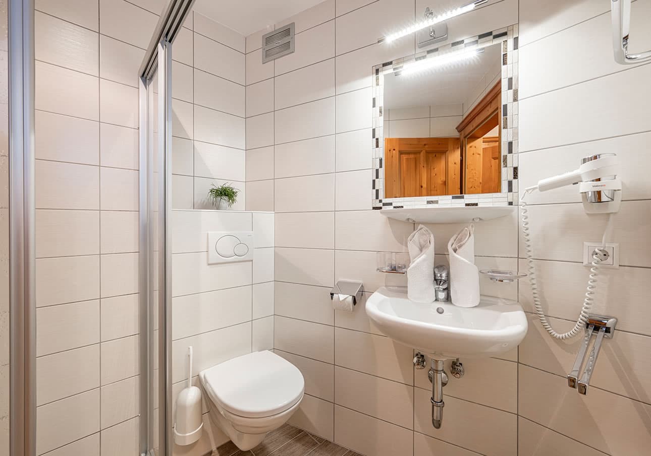 Small modern bathroom with a shower, toilet, and sink under a lit mirror