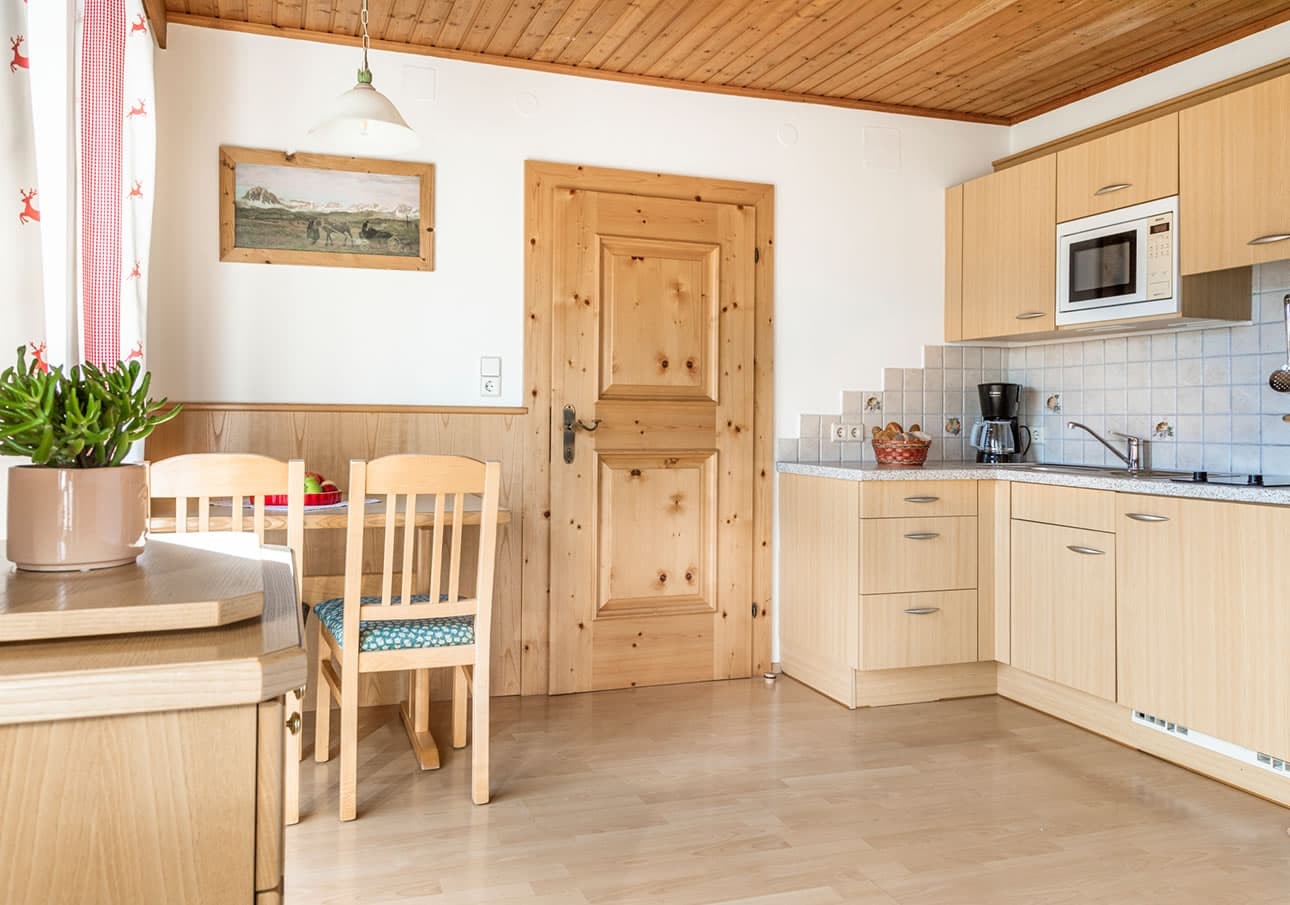 Wooden kitchen with a table, chairs, and modern appliances near a door