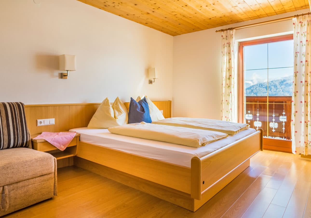 Cozy bedroom with wooden decor, balcony view, and a neatly made bed