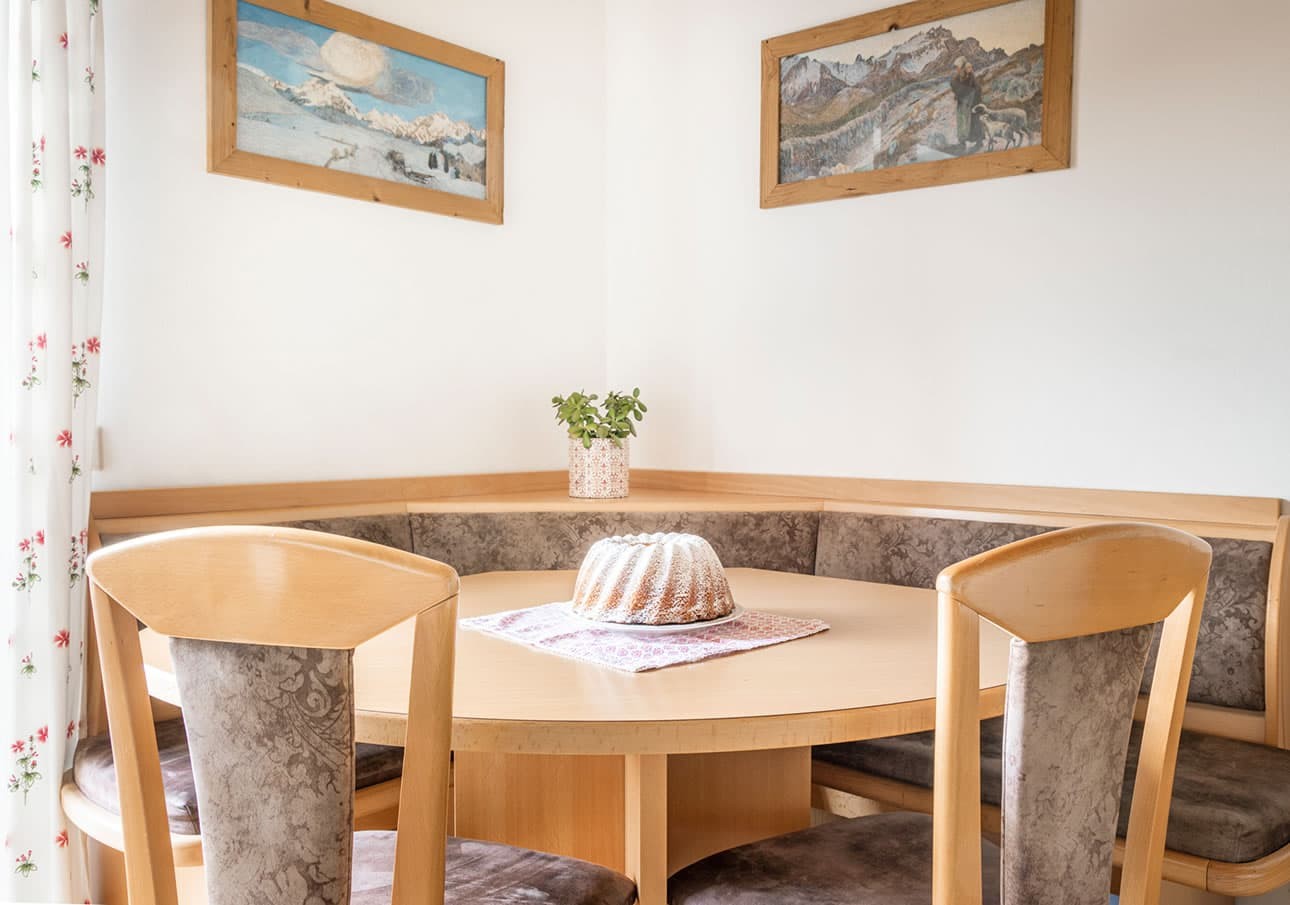 A round dining table with a cake centerpiece in a cozy corner with wall art