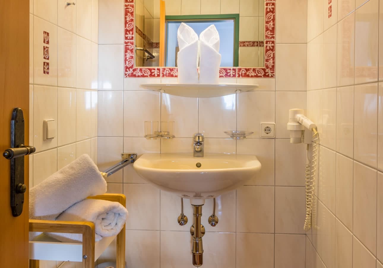 Small bathroom with a sink, mirror, towels, and a hairdryer on the wall