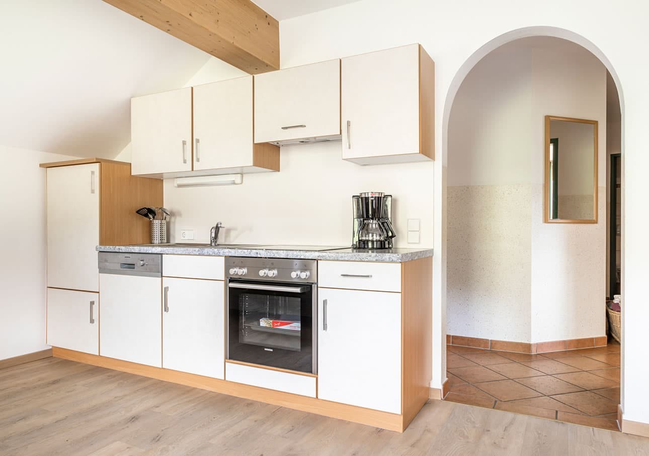 Modern kitchen with white cabinets and stainless steel appliances next to an arched doorway