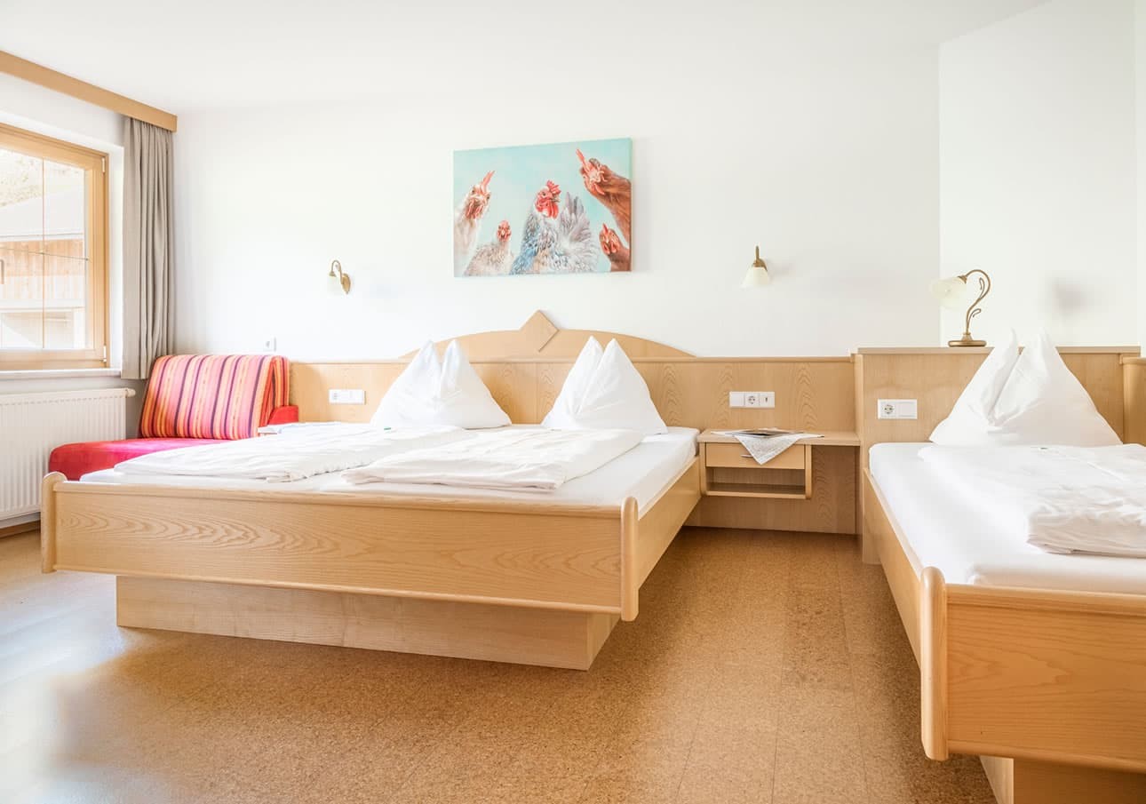 A bright hotel room with two neatly made wooden beds and a colorful painting on the wall