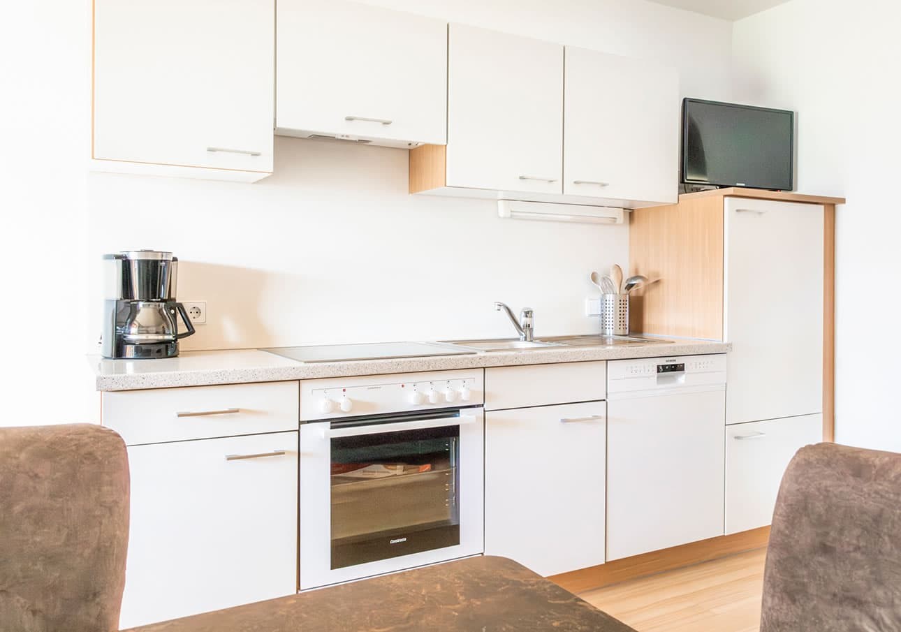 Modern kitchen with white cabinets, coffee maker, and oven
