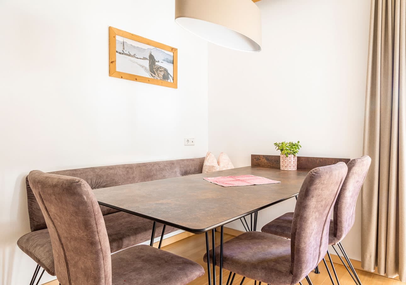 Modern dining room with brown chairs, table, and a plant under a large ceiling light