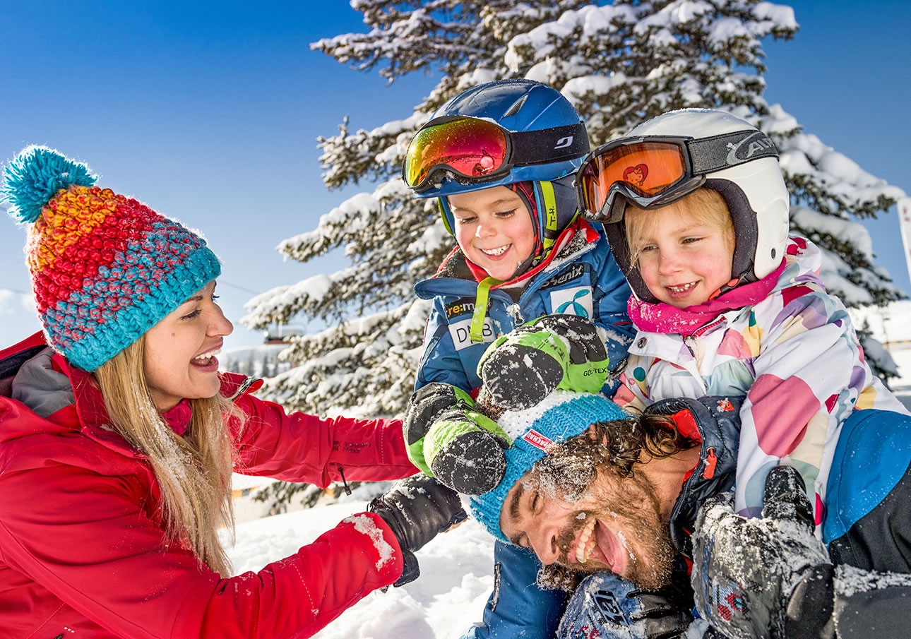 Family enjoys playful snow fun under a blue sky