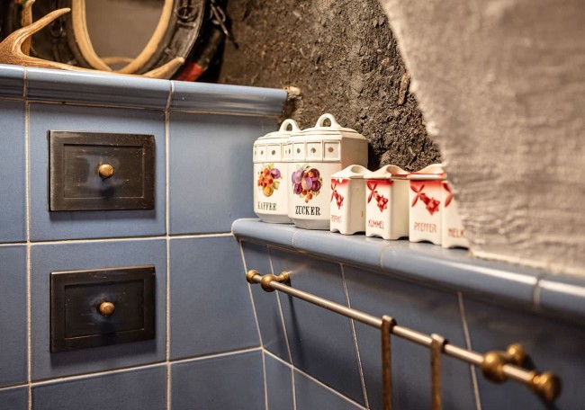 Blaue geflieste Wand mit Gewürzdosen und Handtuchhalter in einer rustikalen Küche