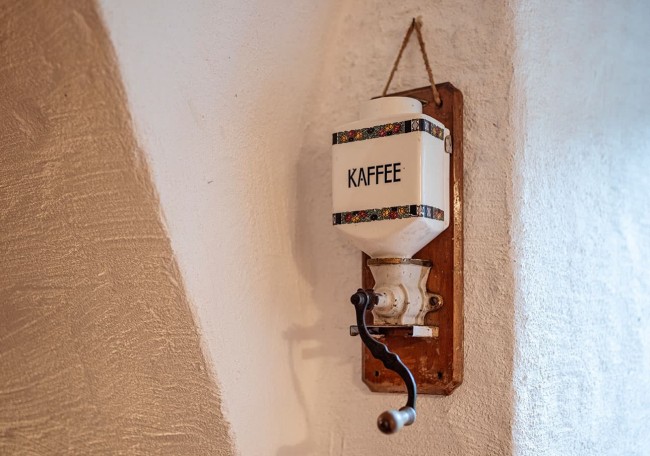 Alte Kaffeemühle an der Wand mit Kurbel; Text "Kaffee"