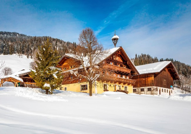 der verschneite Prechtlhof in einer winterlichen Gebirgslandschaft bei blauem Himmel