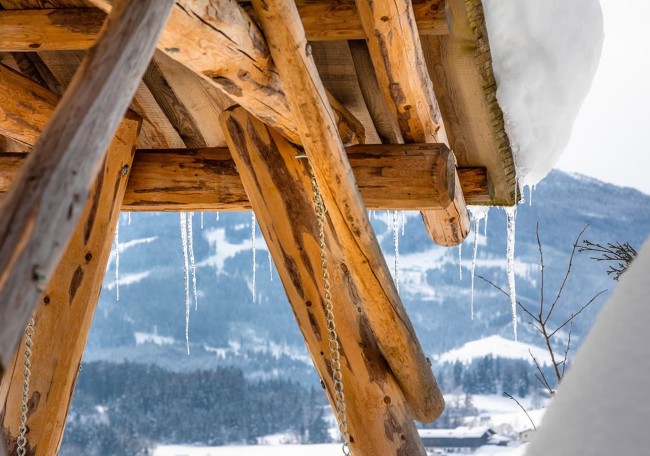 Holzhütte im Schnee mit hängenden Eiszapfen und schneebedecktem Hintergrund