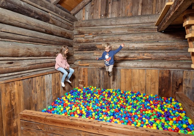 Zwei Kinder spielen in einem Spielestadl in einem Bällebad aus bunten Bällen