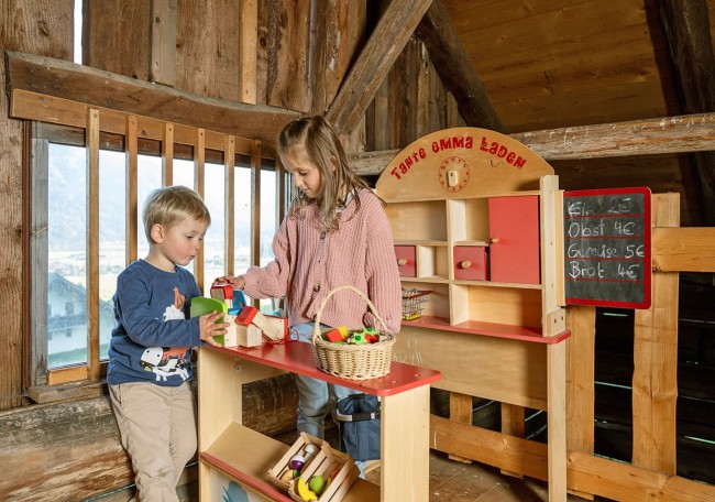 Zwei Kinder spielen in einem hölzernen Kaufmannsladen
