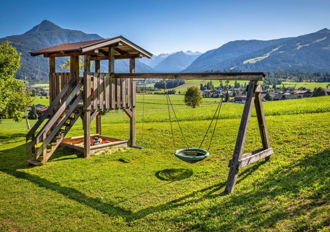 Spielplatz mit Schaukel und Rutsche in malerischer Berglandschaft