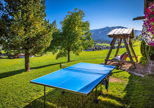 Ein blauer Tischtennistisch steht auf einer grünen Wiese mit Bergblick im Hintergrund