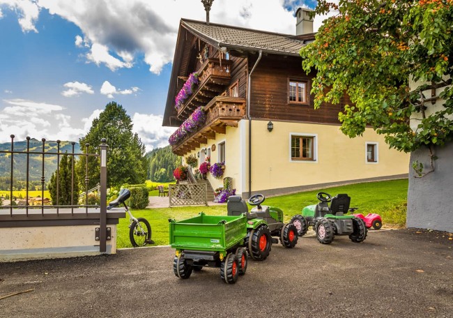 Spielzeugtraktoren stehen vor einem traditionellen Prechtlhof mit Blumenbalkonen