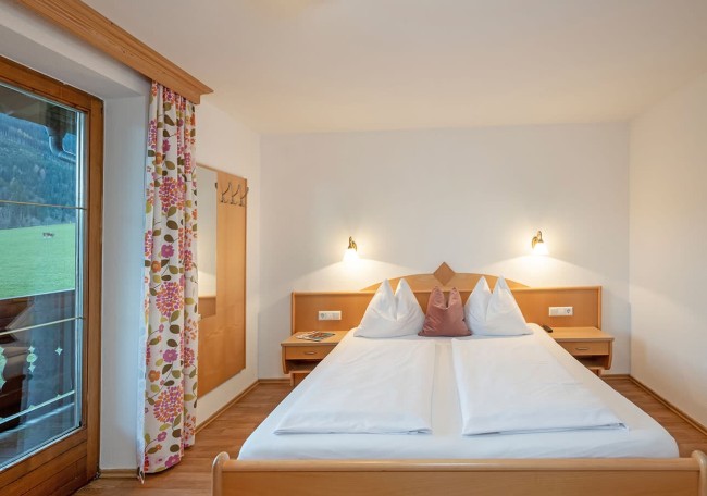 Helles Schlafzimmer mit Doppelbett, Holzdekor und großem Fenster mit Vorhängen