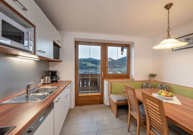 Moderne Küche mit Esstisch, Stühlen und Blick auf die Berge durch ein großes Fenster