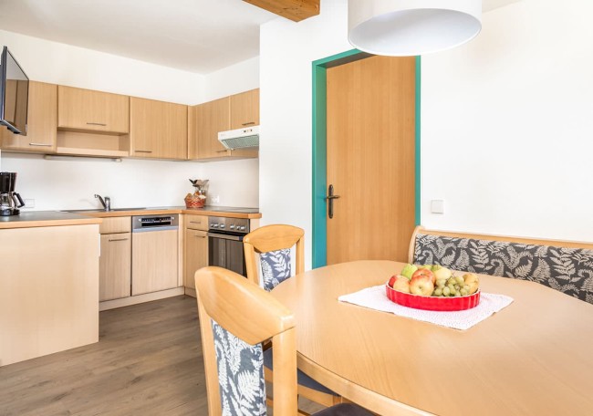 Moderne Küche mit Holzschränken, Esstisch, Obstschale und Sitzbank