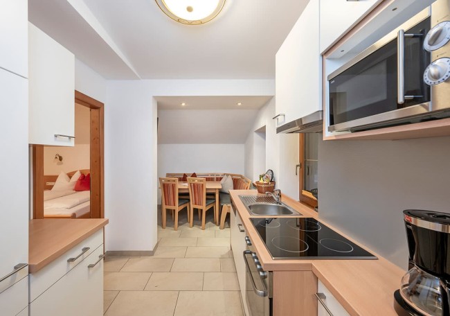 Moderne Küche mit Elektroherd und Mikrowelle neben einem Essbereich mit Holzstühlen