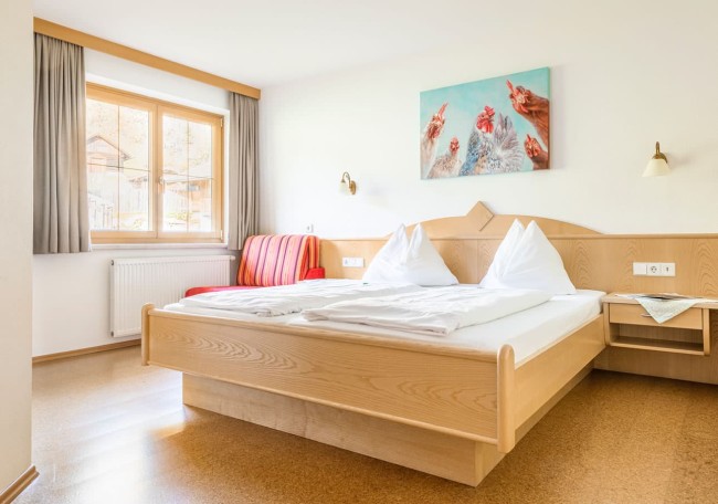 Helles Zimmer mit Doppelbett, Sofa und Bild an der Wand