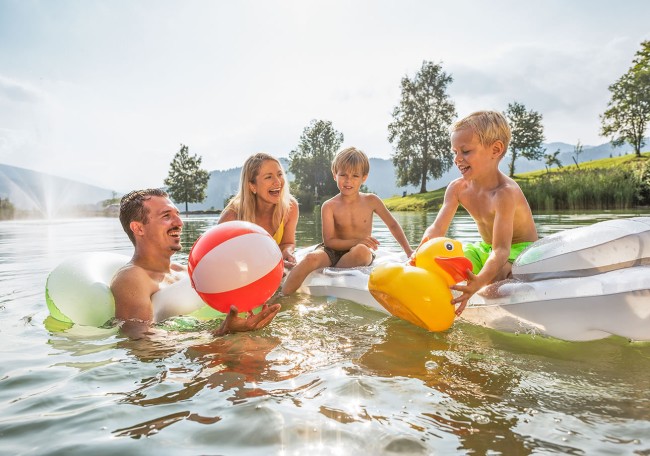 Familie schwimmt lachend im Badesee Flachauwinkel