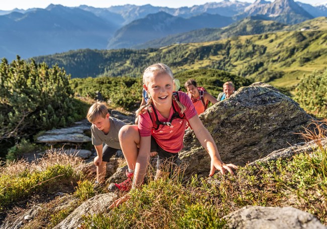 Eine Gruppe von Kindern klettert auf einem felsigen Pfad in einer Berglandschaft