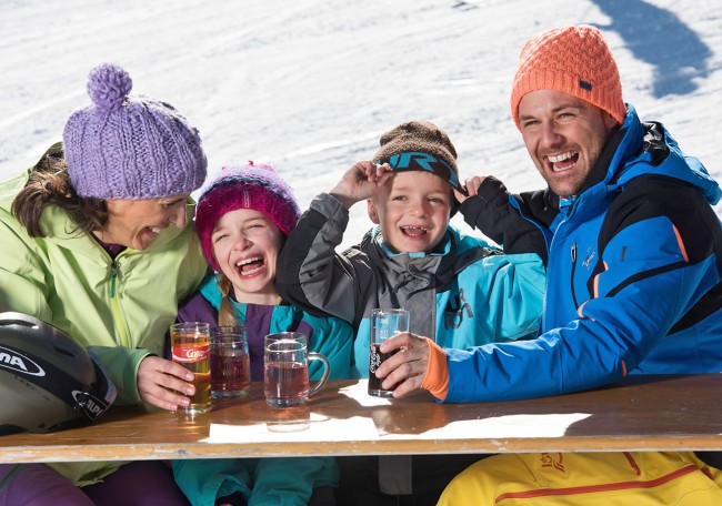Familie lacht und trinkt am Tisch in Schneelandschaft