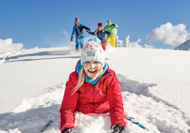Vier Menschen haben Spaß im Schnee bei sonnigem Winterwetter