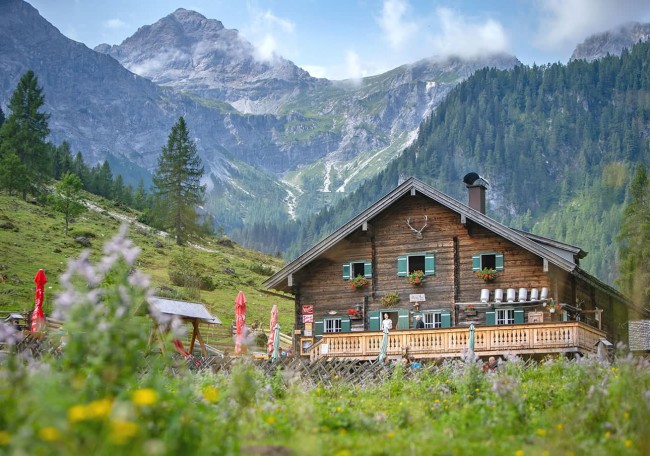 Prechtlhütte in alpiner Landschaft mit Bergen und Wiese im Hintergrund
