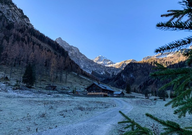 Die Prechtlalm liegt friedlich in einem Tal, umgeben von Bergen und Wäldern unter blauem Himmel