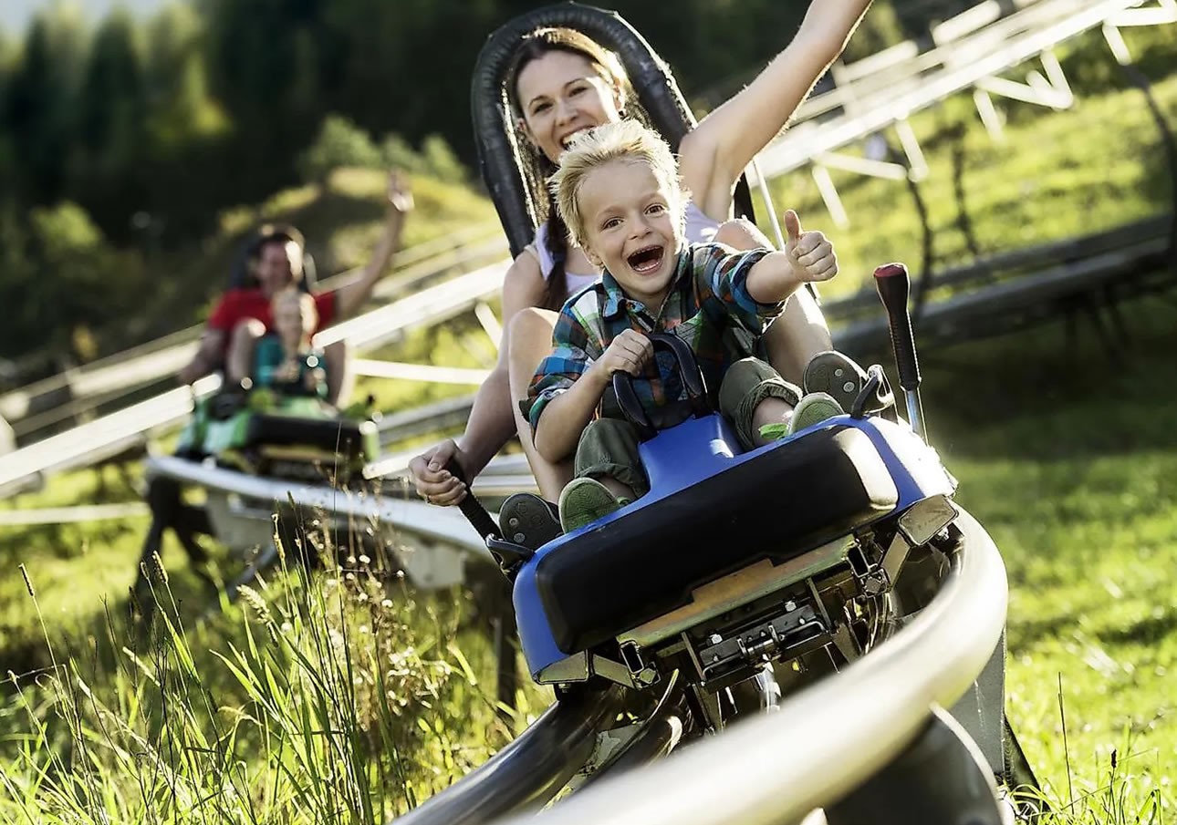 Mother and child are laughing while riding the Alpine Coaster Lucky Flitzer in Flachau