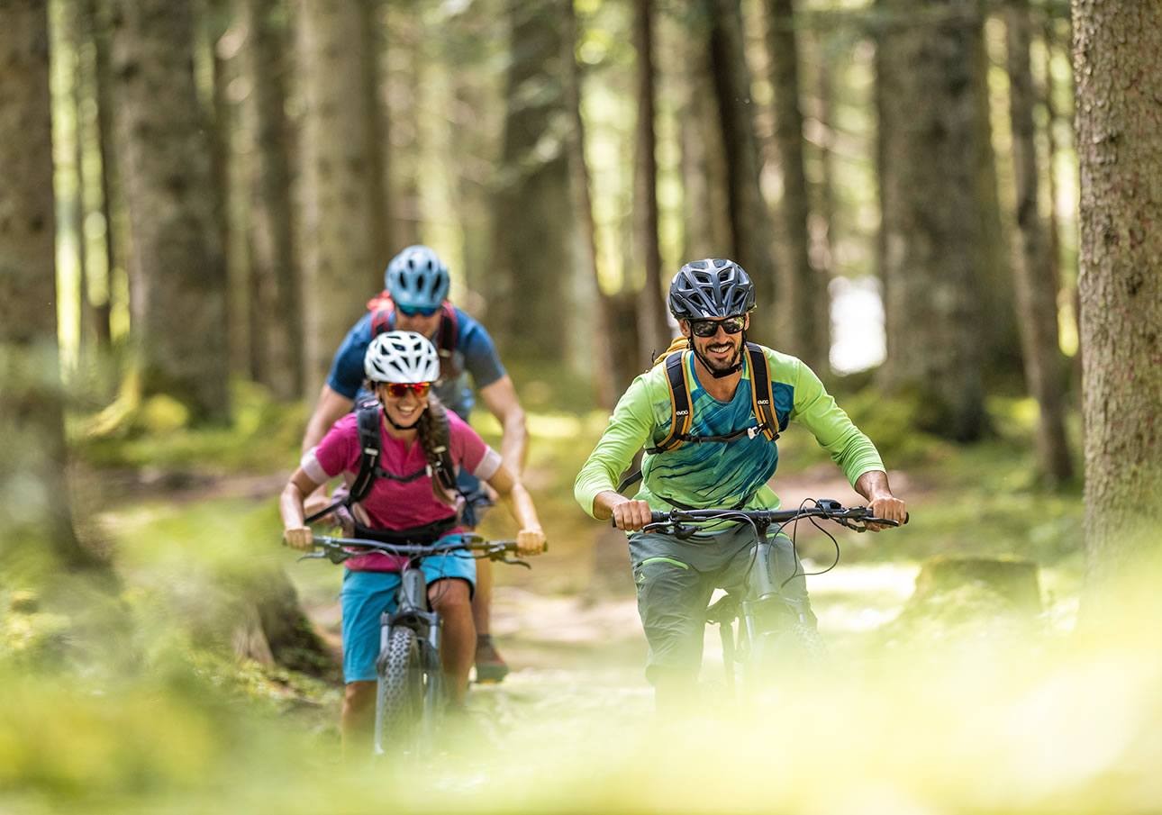 Friends ride in the forest during a mountain bike tour in Flachau